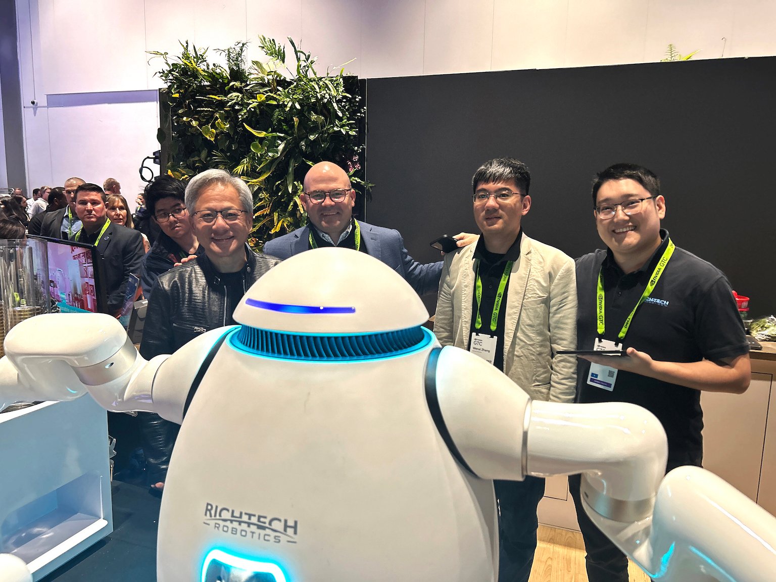 four people stand behind bartender robot