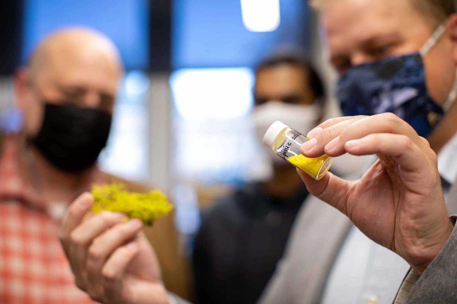 a scientist retaining a vial of yellow powder