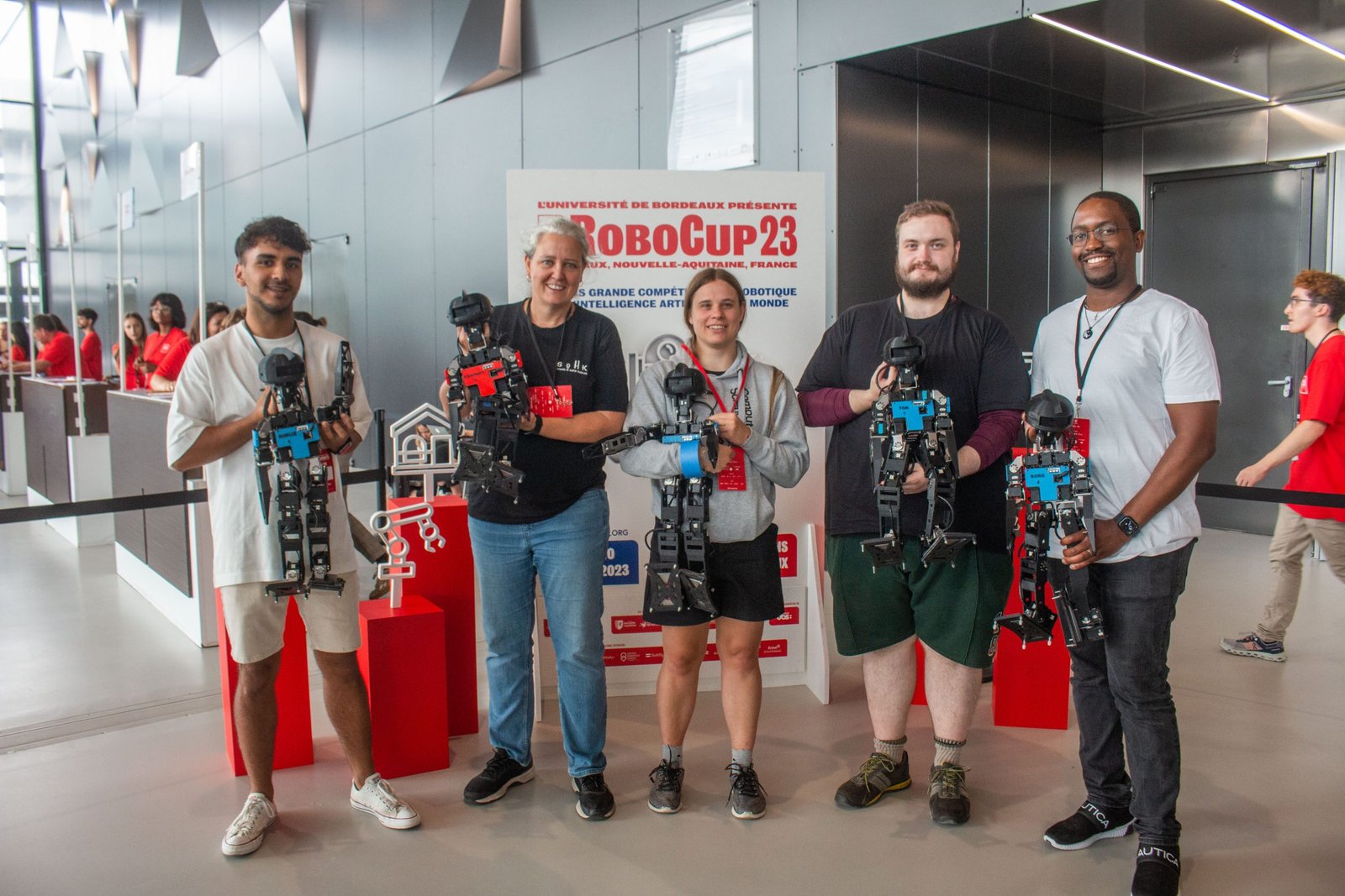 Five people holding kid-sized robots