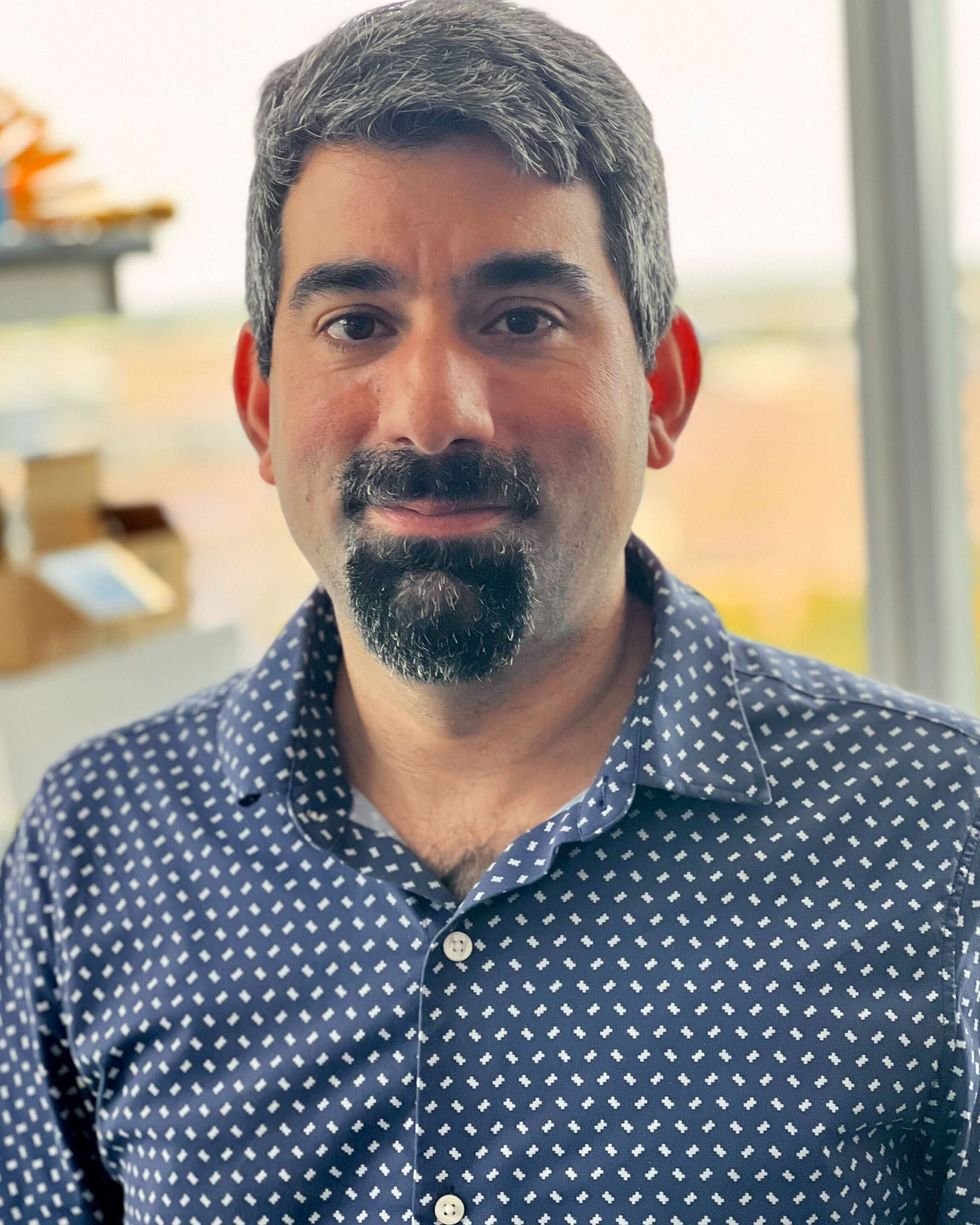 a man with a beard wearing a polka dotted button-up shirt posing for a portrait