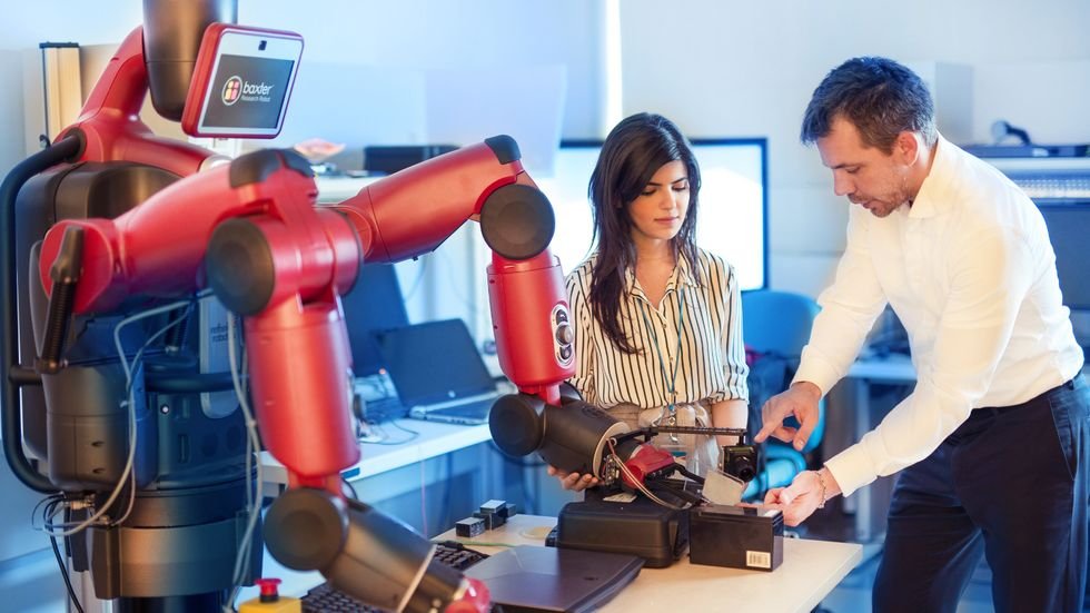 A photo of two people in front of a red robot.