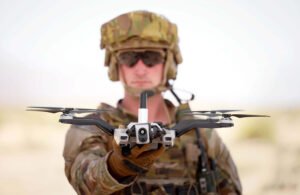 A solder in camo and sunglasses looking into the camera and holding Red Cat's Black Widow drone. The company won an Air Force contract in November 2024.