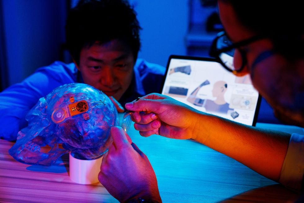 Two people work on a skull with a device attached to it.