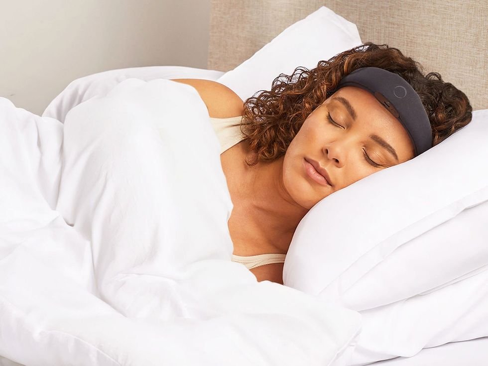 woman sleeping in bed with black headband looking wearable on her forehead