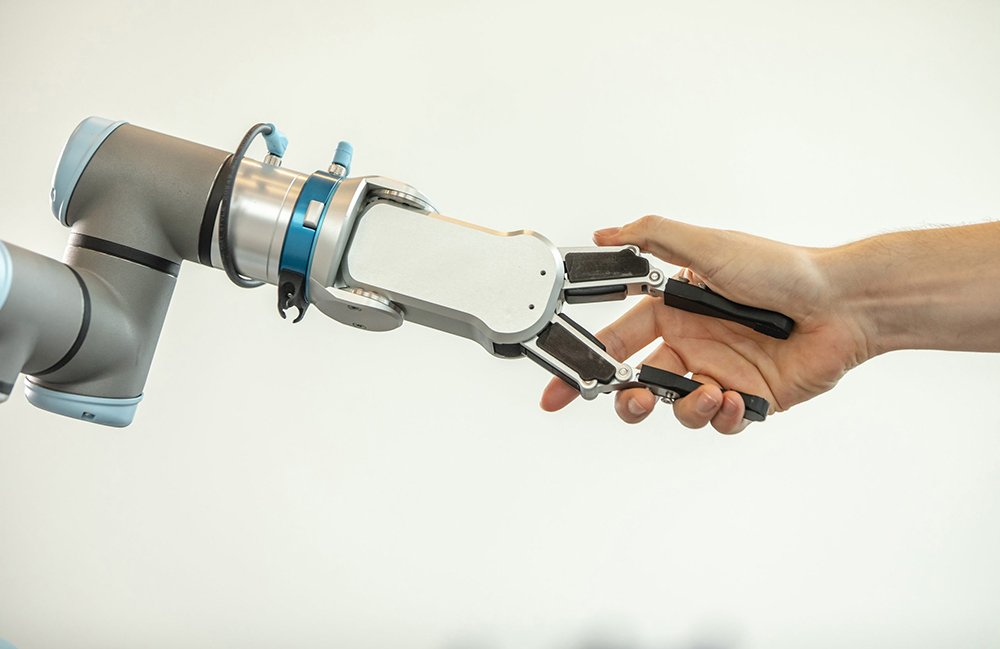 A person shaking hands with a cobot arm with a two-fingered gripper.